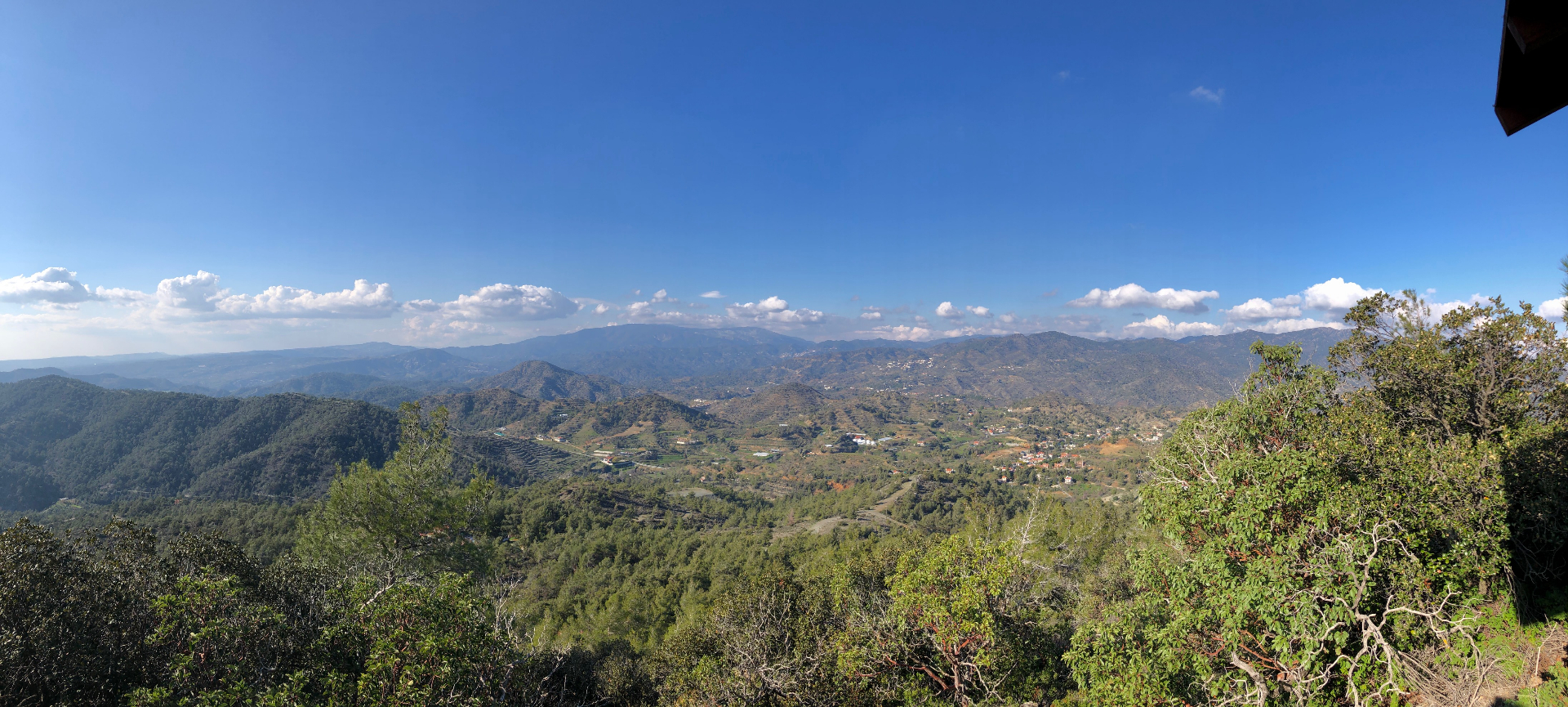 Wide panoramic view of green valleys and distant Troodos mountains from the descent