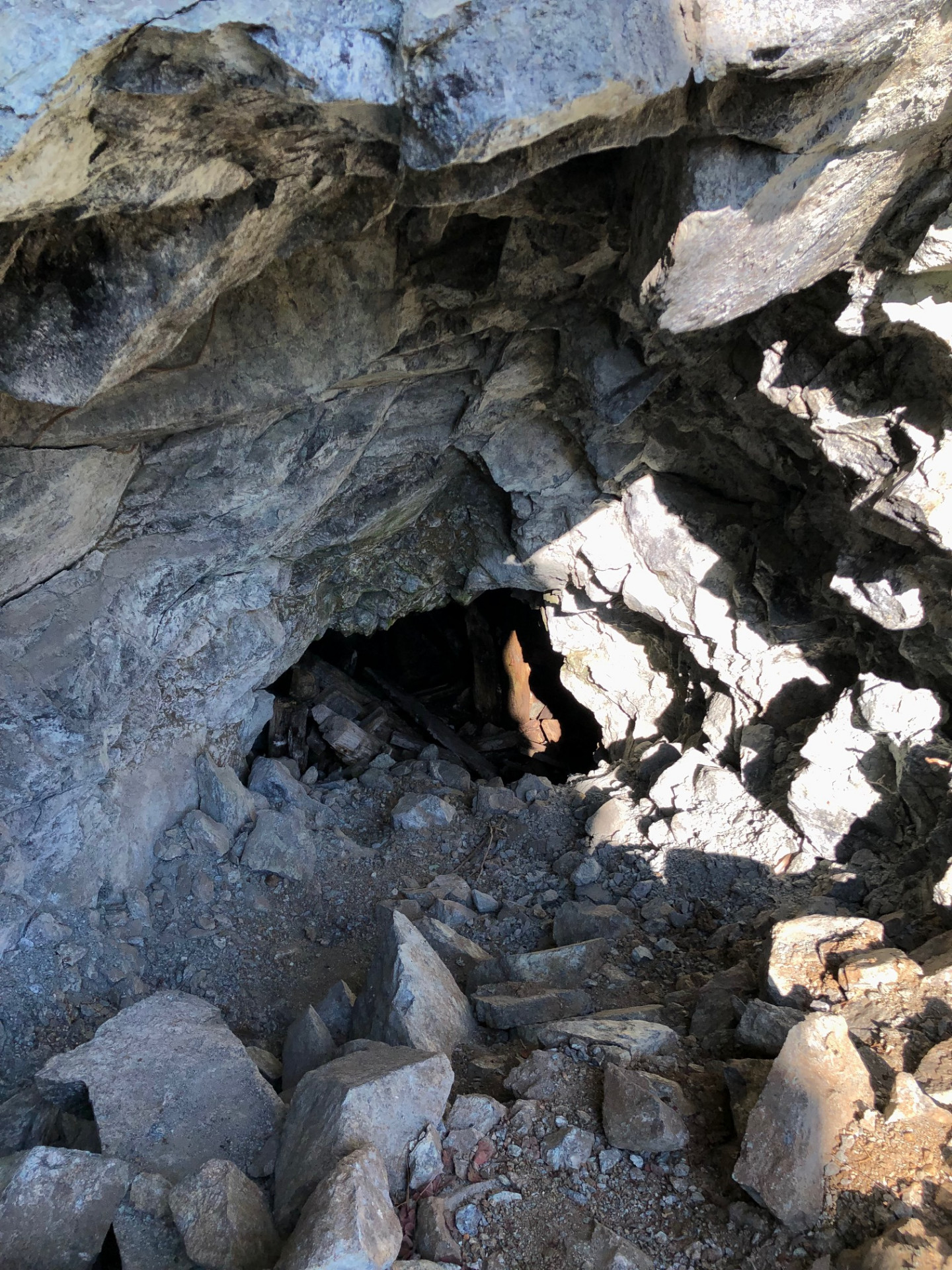 Collapsed entrance to an abandoned mine gallery with old timber supports inside