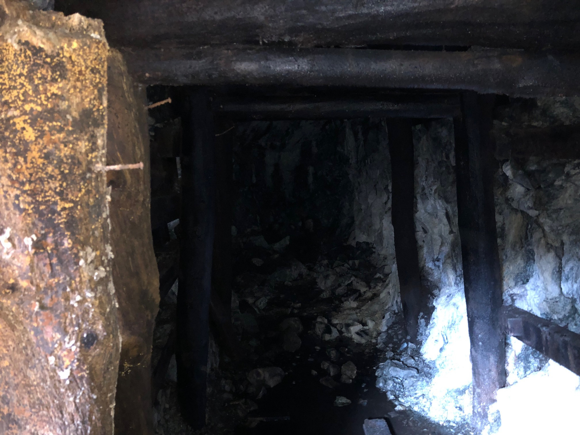 Inside the abandoned mine tunnel, wooden beams framing the darkness