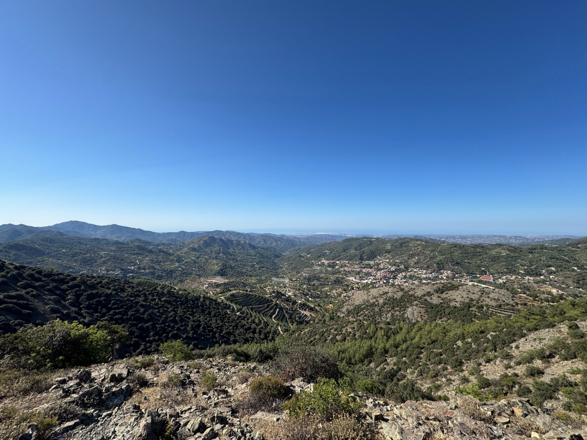 A wide vista over vineyard terraces and a village in the valley from a rocky ridge