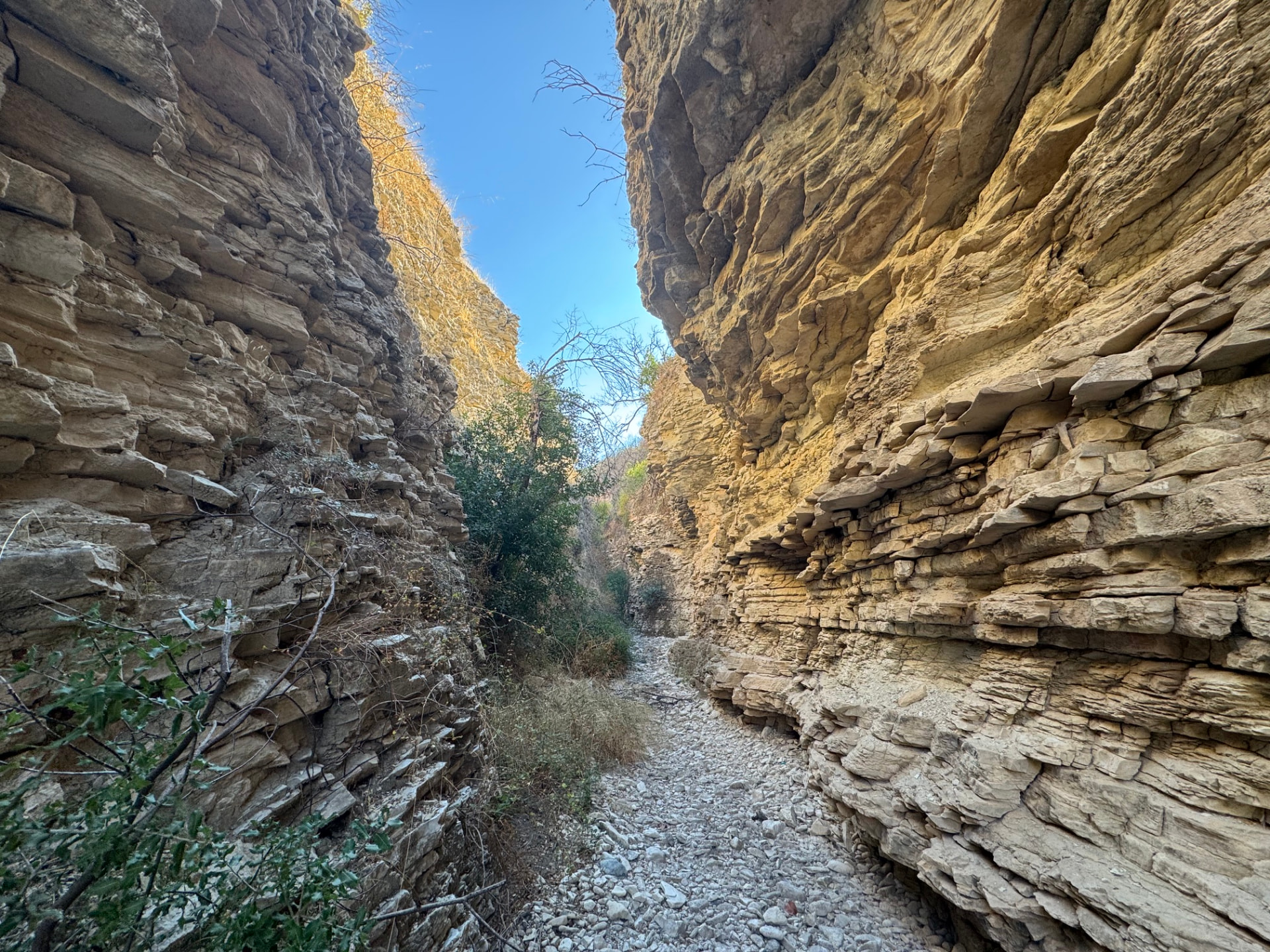 A narrow corridor of the gorge with a floor of white pebbles between layered walls