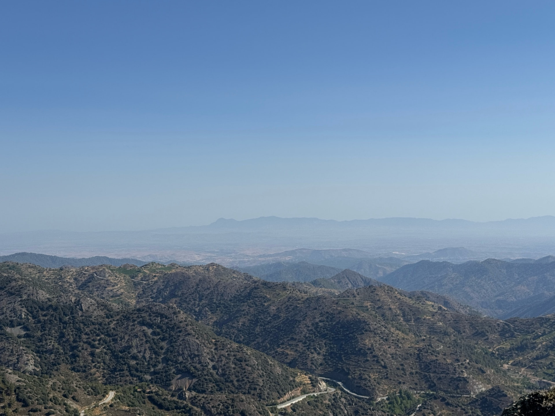 Layered mountain ridges stretching toward a hazy horizon seen from Papoutsa peak