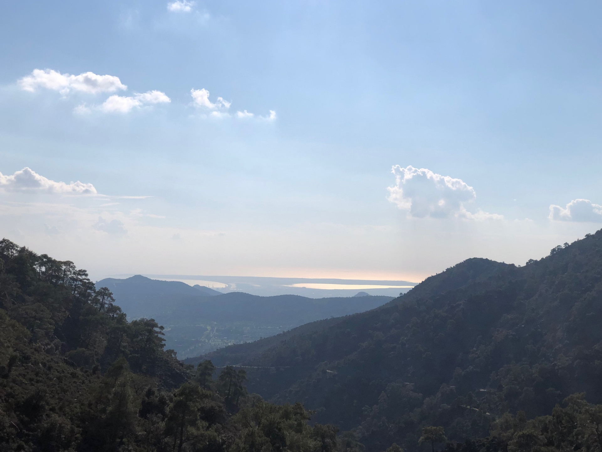 Distant sliver of the Mediterranean sea seen between forested ridges