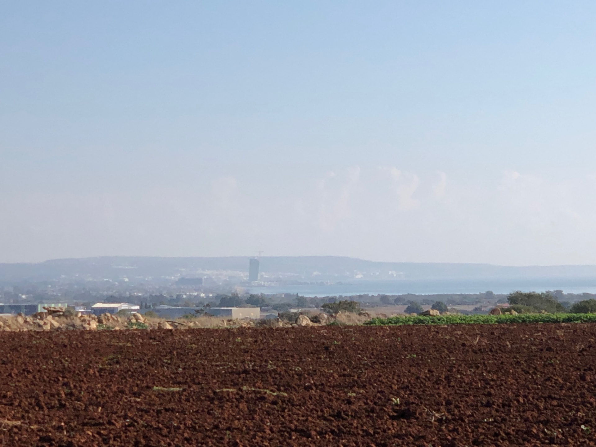 Distant view of the Ayia Napa Marina tower rising above the horizon from the Xylophagou fields