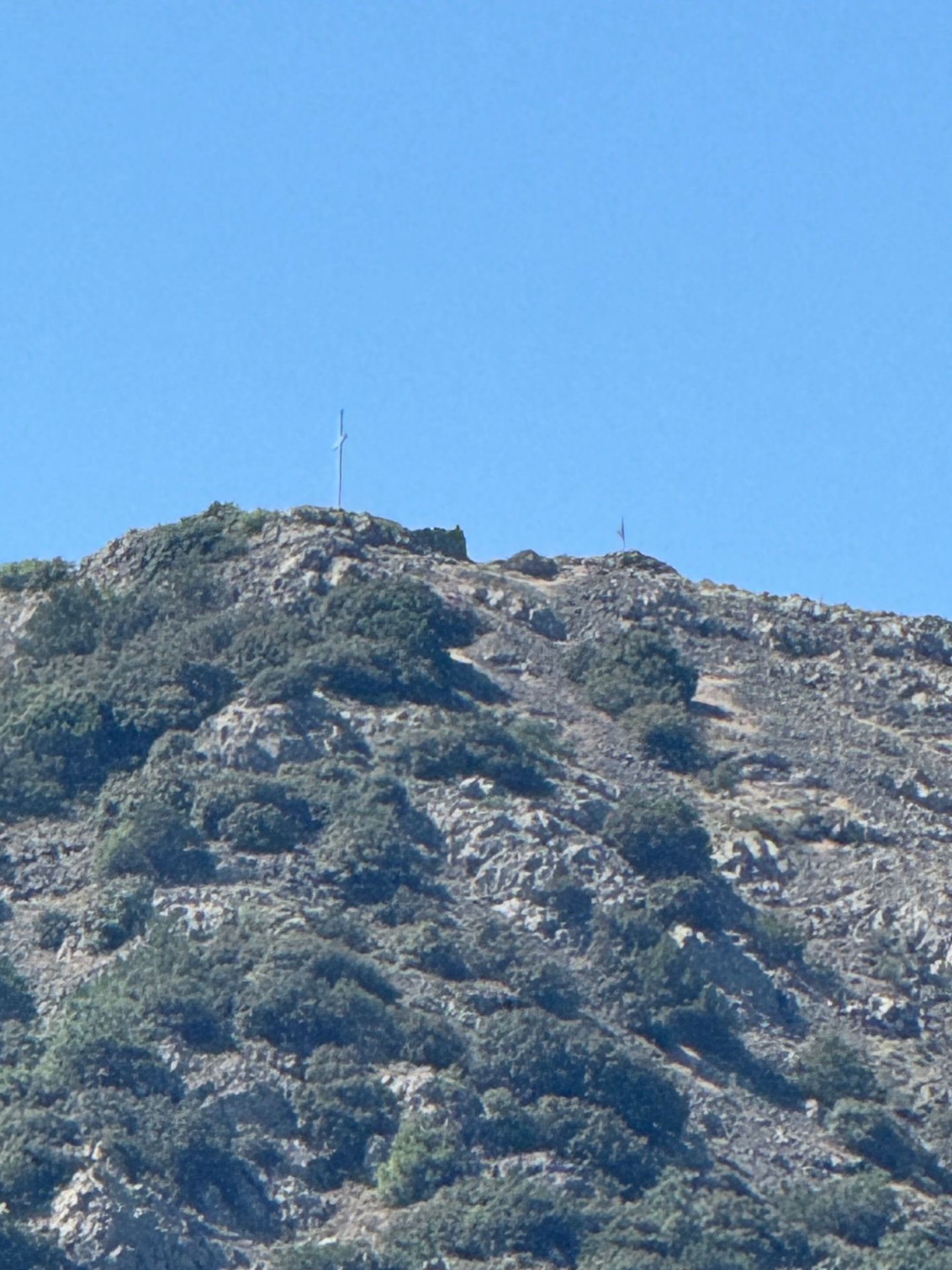 A slender cross on a rocky mountain ridge