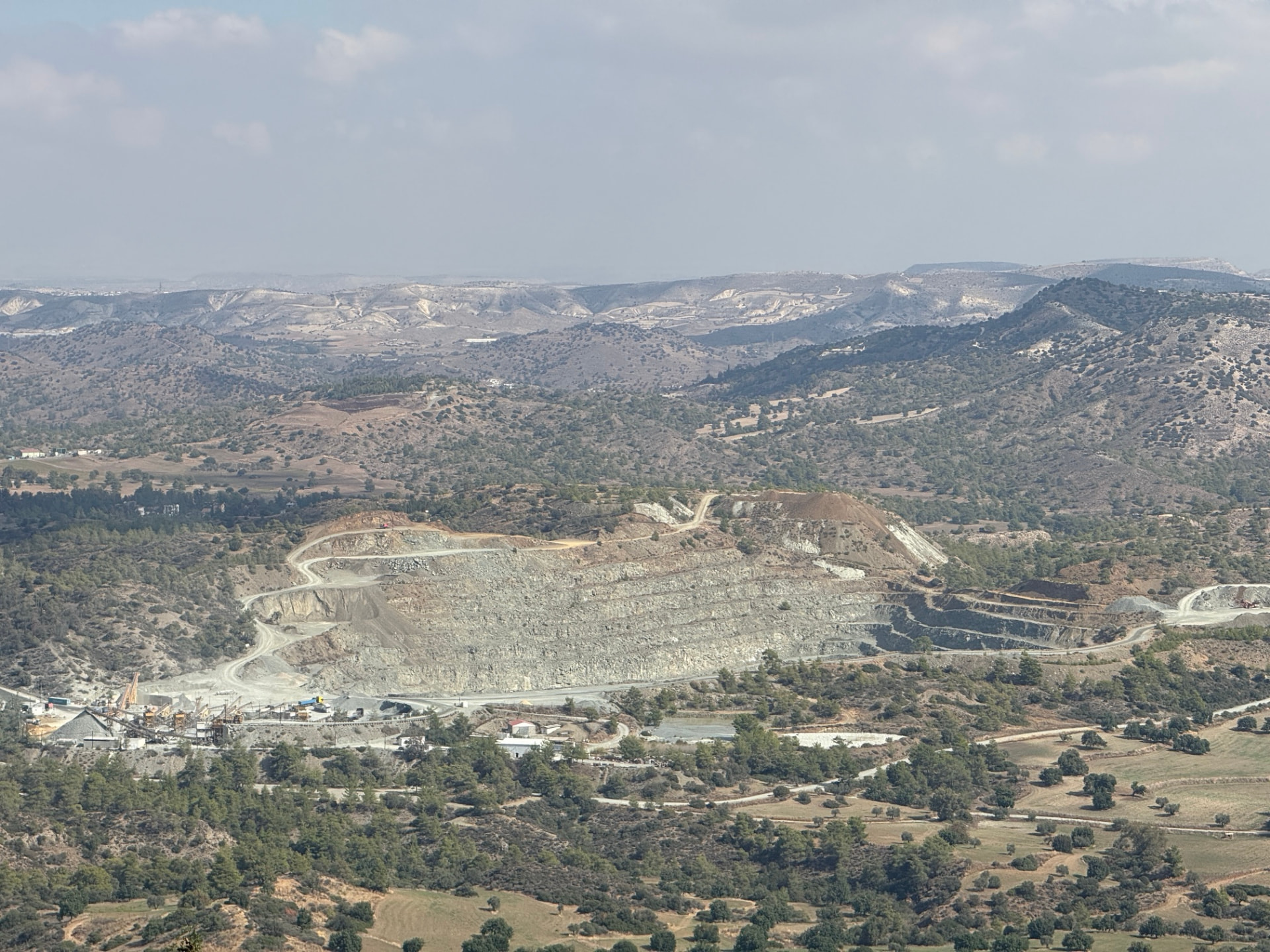 A pale quarry carved into the hills, seen from above