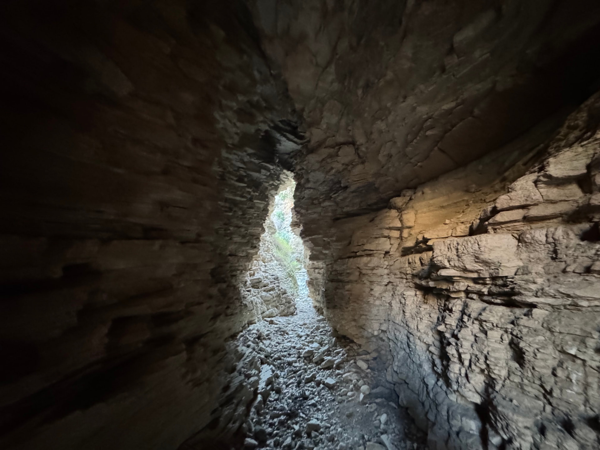 Looking out from a dark cave passage towards a narrow slice of daylight in the gorge