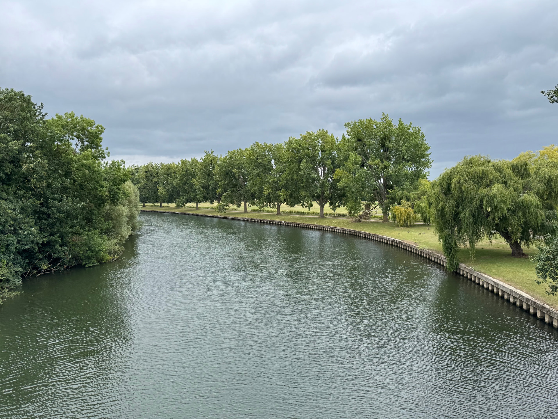 The Thames Path winding beside the river beneath a cloudy sky